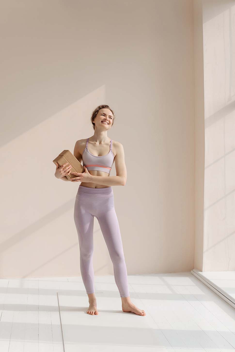 Frau mit pinker Yoga Kleidung praktiziert Yoga mit zwei Yoga Blöcken