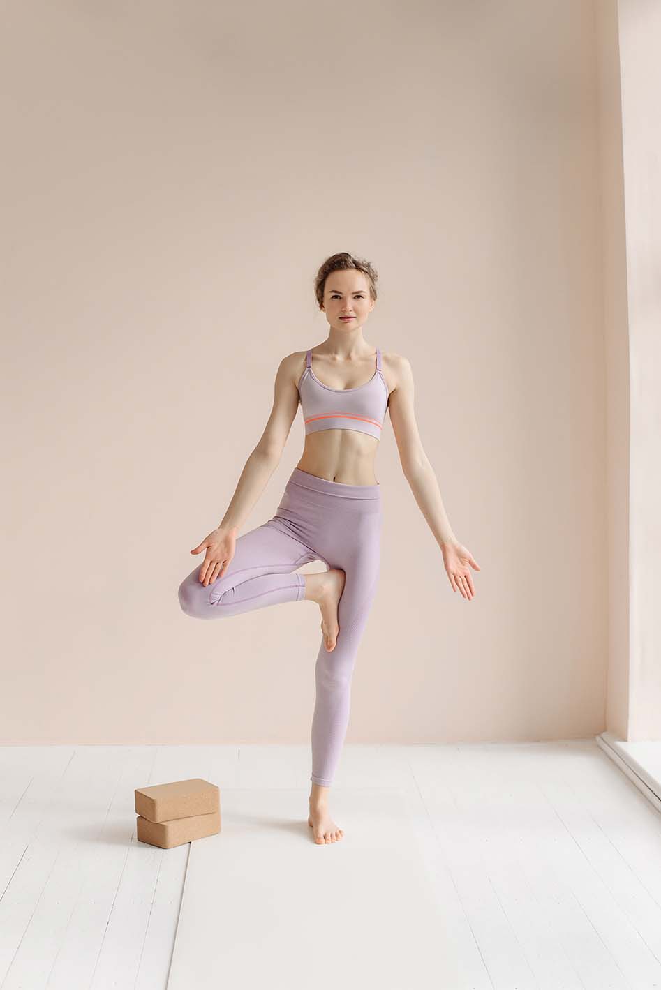 Frau mit pinker Yoga Kleidung praktiziert Yoga mit zwei Yoga Blöcken