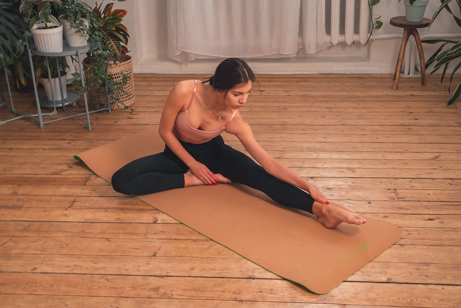 Junge Frau mit pinken Oberteil und schwarzer Leggings praktiziert Yoga auf der Bondella Ahimsa Kork Yogamatte